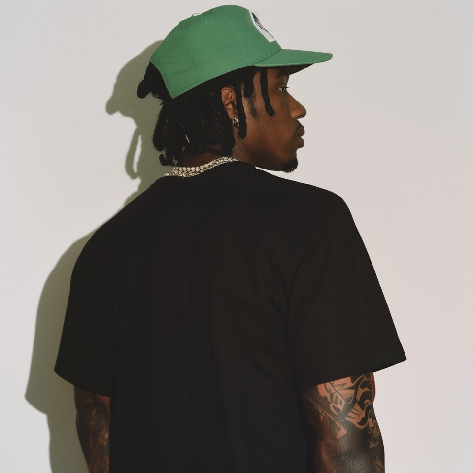 Streetwear model in black t-shirt and green cap representing MuddyStock’s bold urban style.